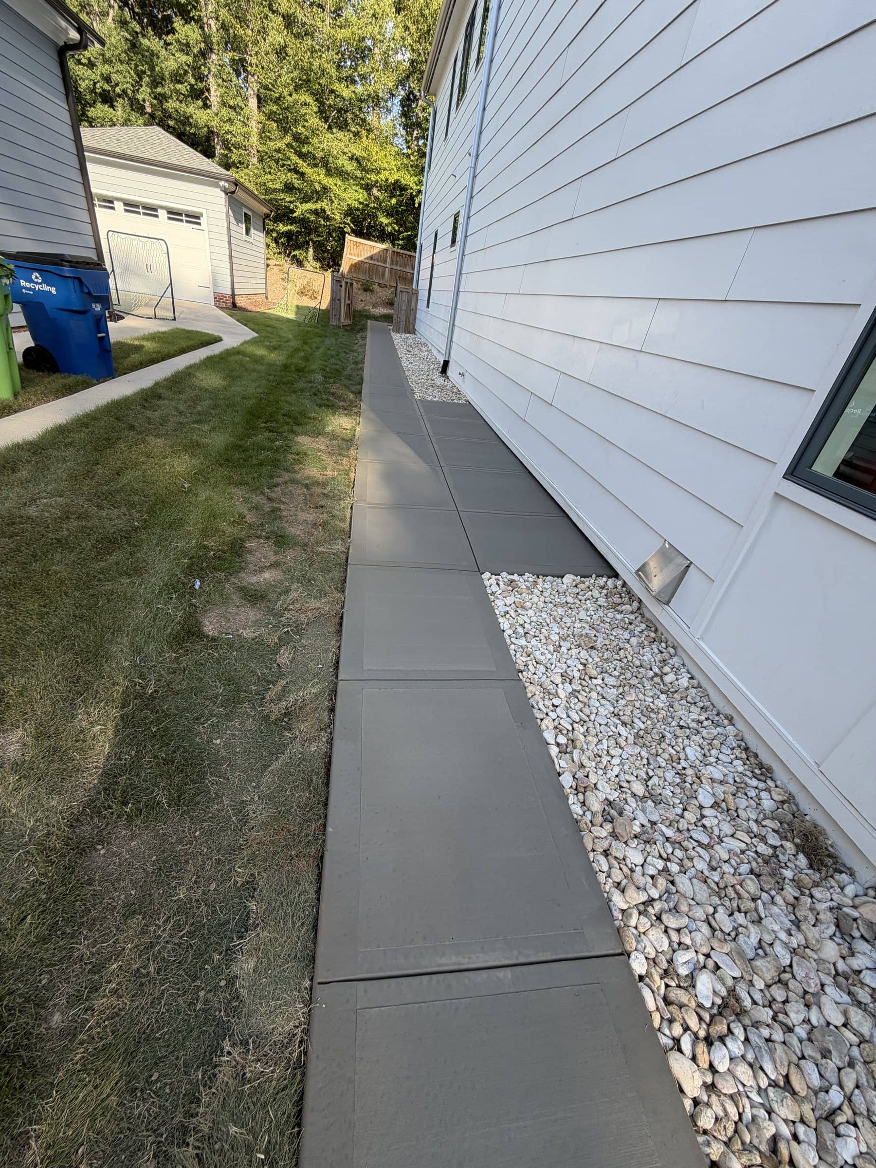 Concrete side walkway next to a river-rock border at a home in Raleigh, NC