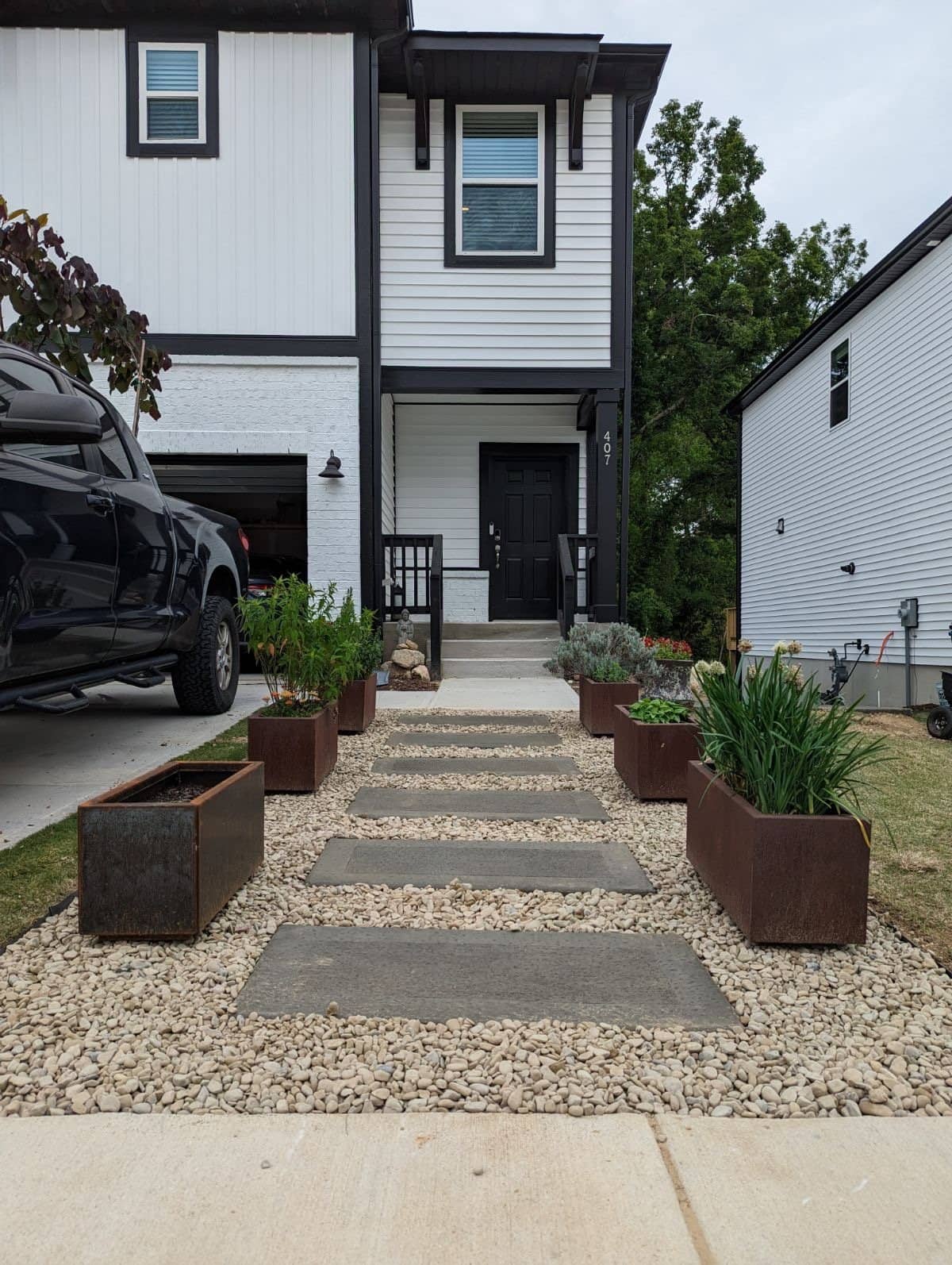 Front walkway of concrete pads, gravel and steel planters